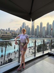 Joelle Monroe auf einem Balkon mit der Skyline von Dubai im Hintergrund.