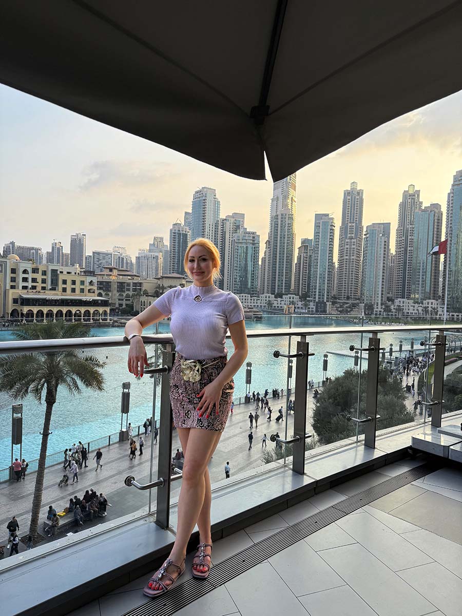 Joelle Monroe on a balcony with the Dubai skyline in the background.
