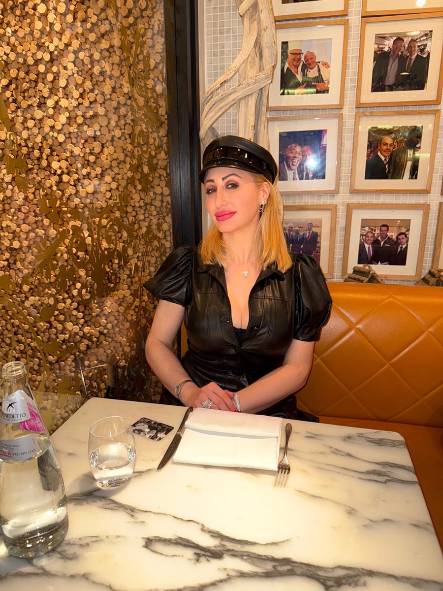 Joelle Monroe in a black dress sitting at a table in a restaurant.